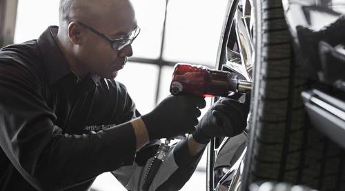 A mechanic fitting a GMC tire to vehicle