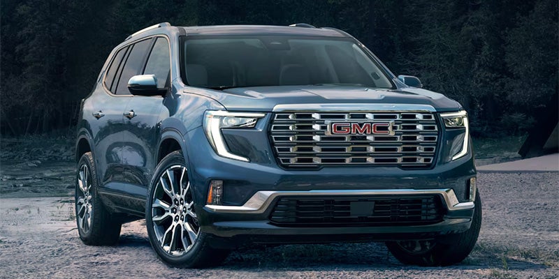 Blue Acadia car parked front of trees