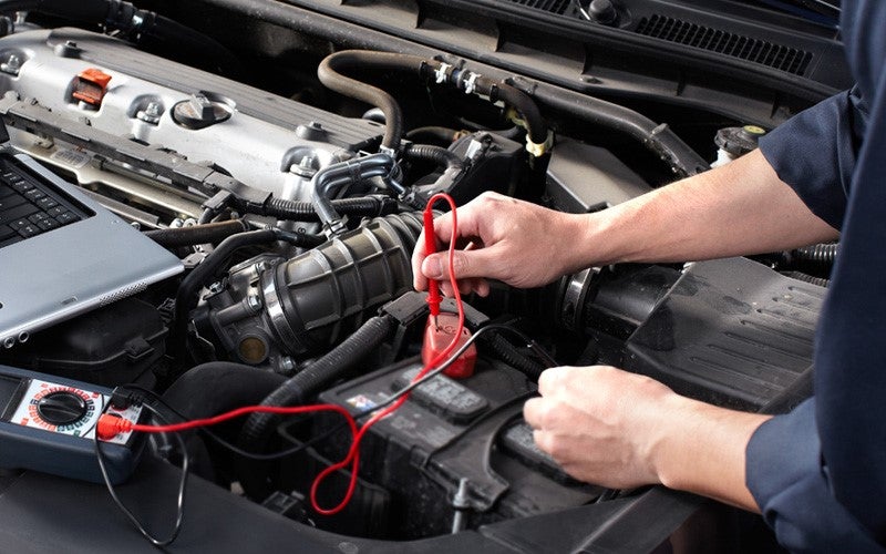 A mechanic installing a GMC battery into the vehicle