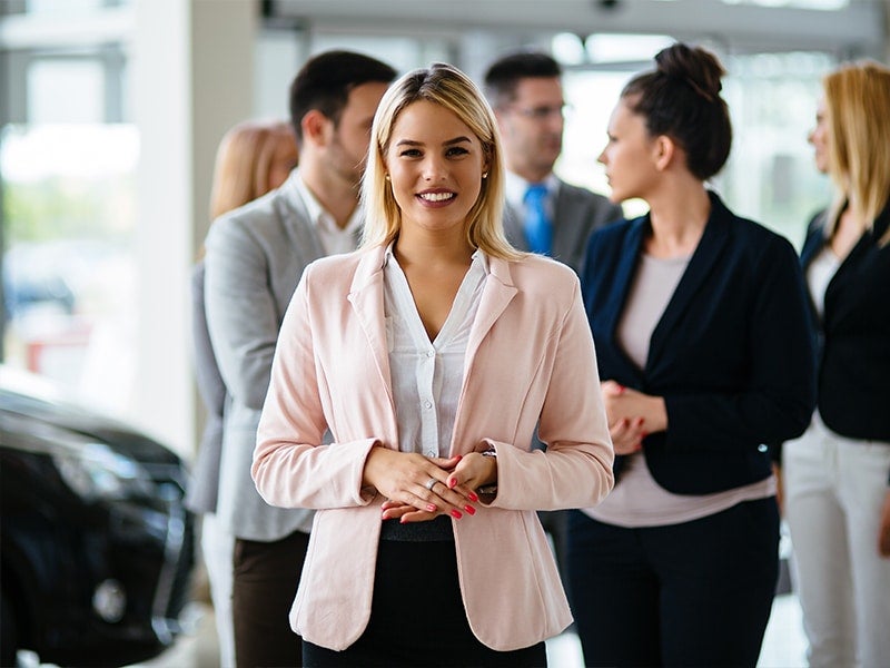 A women is standing front of team with smile