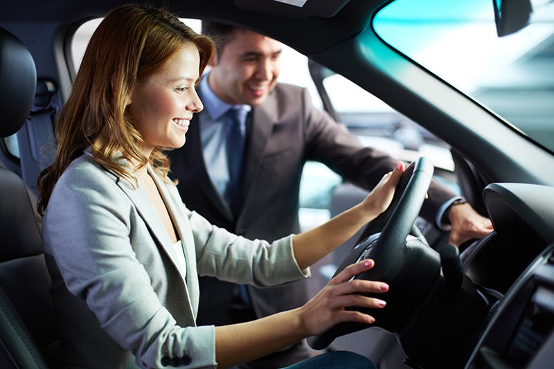 A women is seating on driving seat and salesperson talking with her